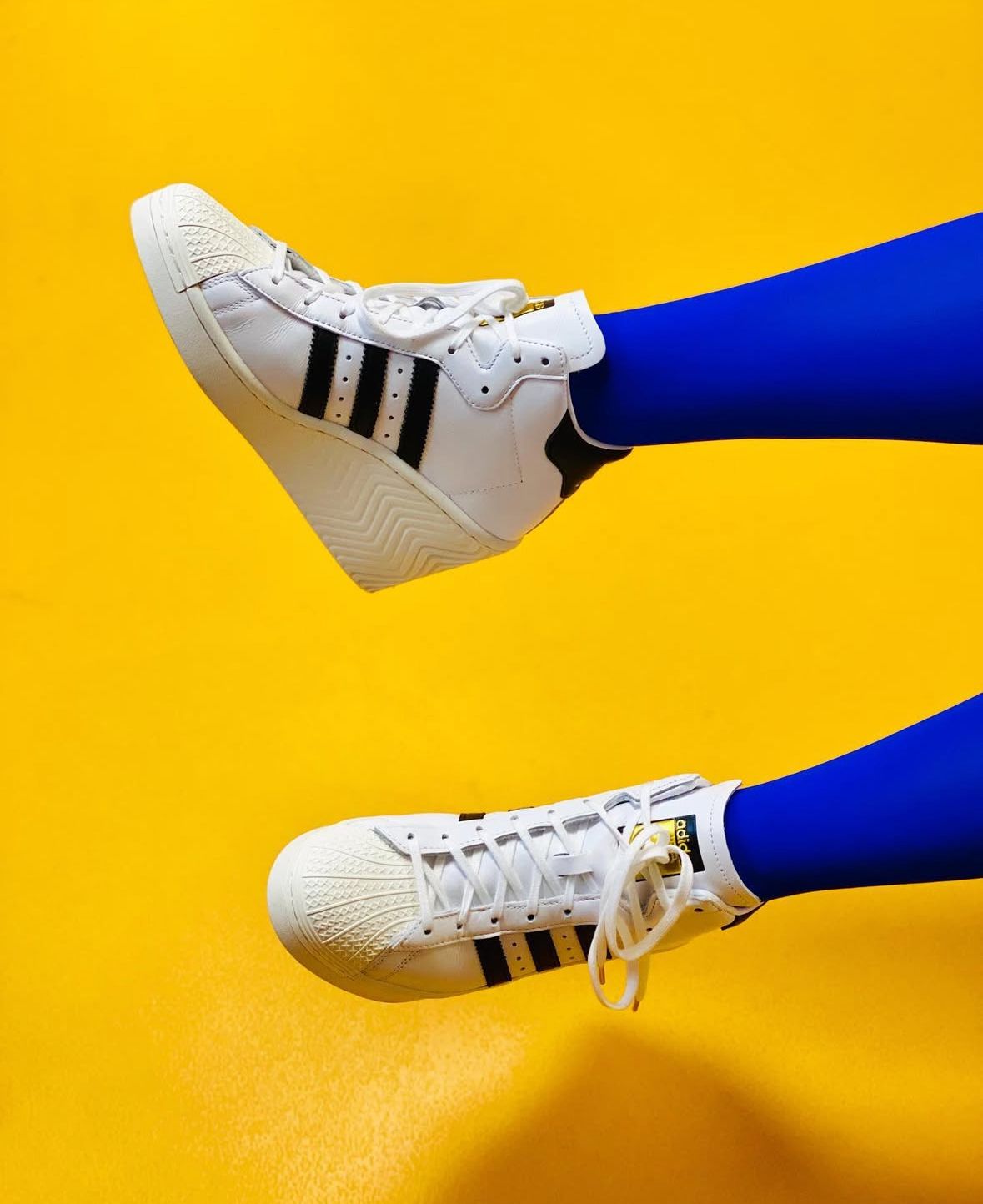 adidas sneaks på blå ben på gul baggrund