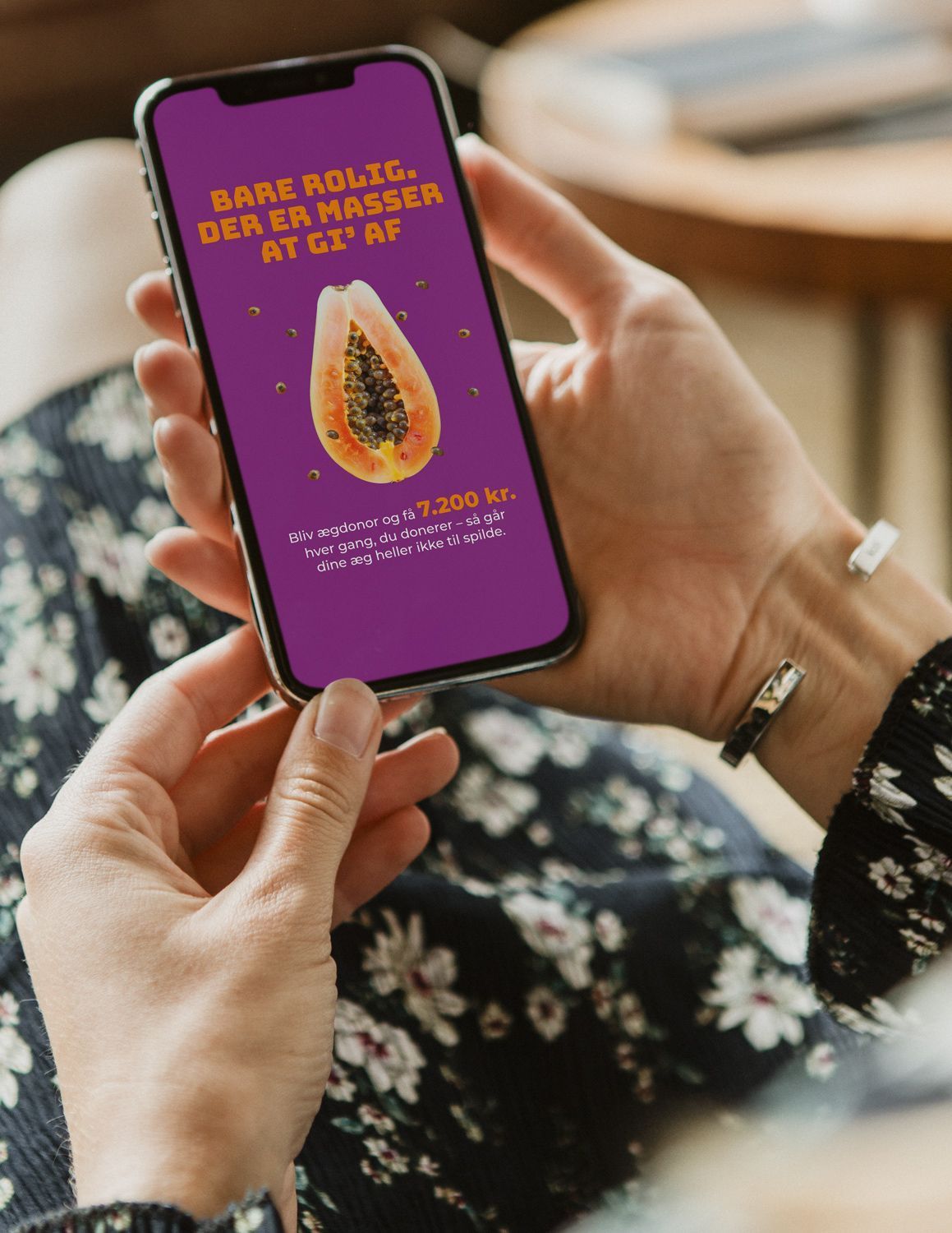 Billedet viser en kvinde som sidder med sin telefon i hånden, som viser en kampagne for ægdonor.nu
